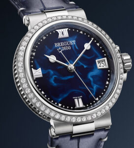 Luxusní dámské hodinky Breguet Marine Dame s modrým číselníkem inspirovaným hlubinami oceánu, diamantovou lunetou a řemínkem z modré aligátoří kůže.